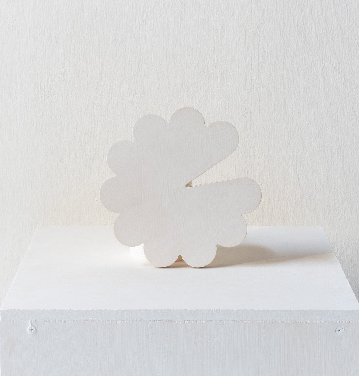 White cloud-shaped object on a white surface with a white background